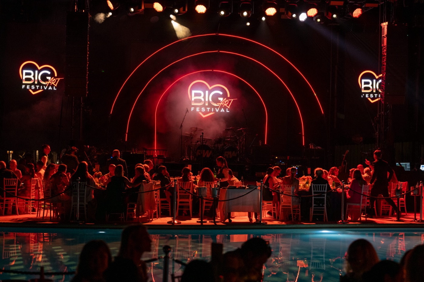 Guests seated at the BIG ART Festival gala dinner beside the pool at Romazzino, A Belmond Hotel